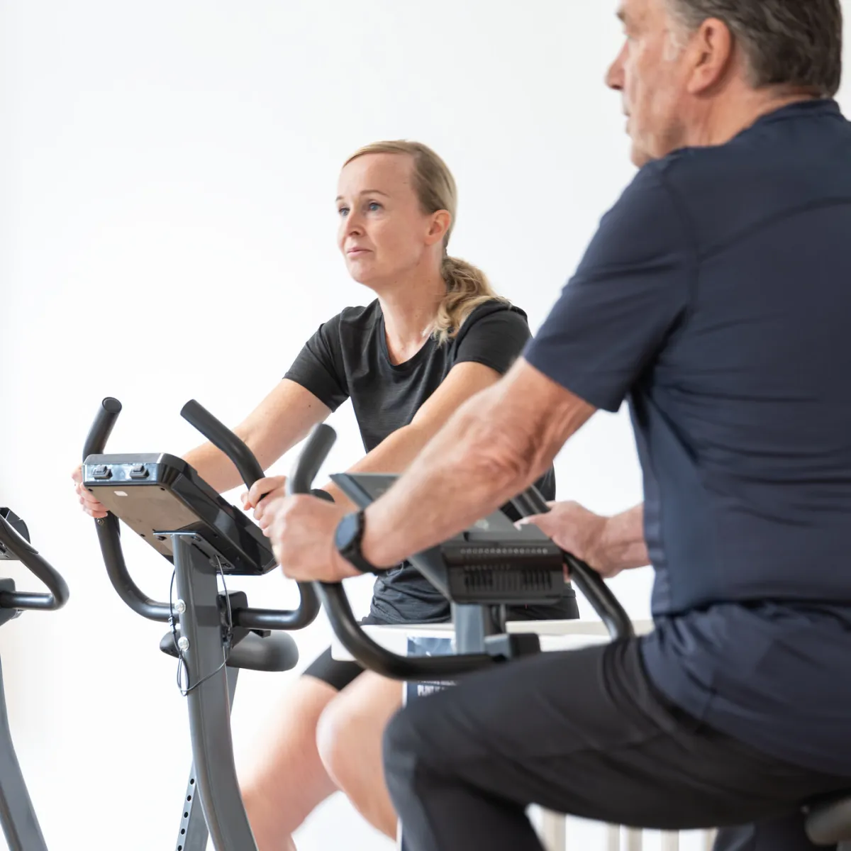 Twee klanten trainen geconcentreerd op de fietsen in de Mpowher Huiskamer Gym